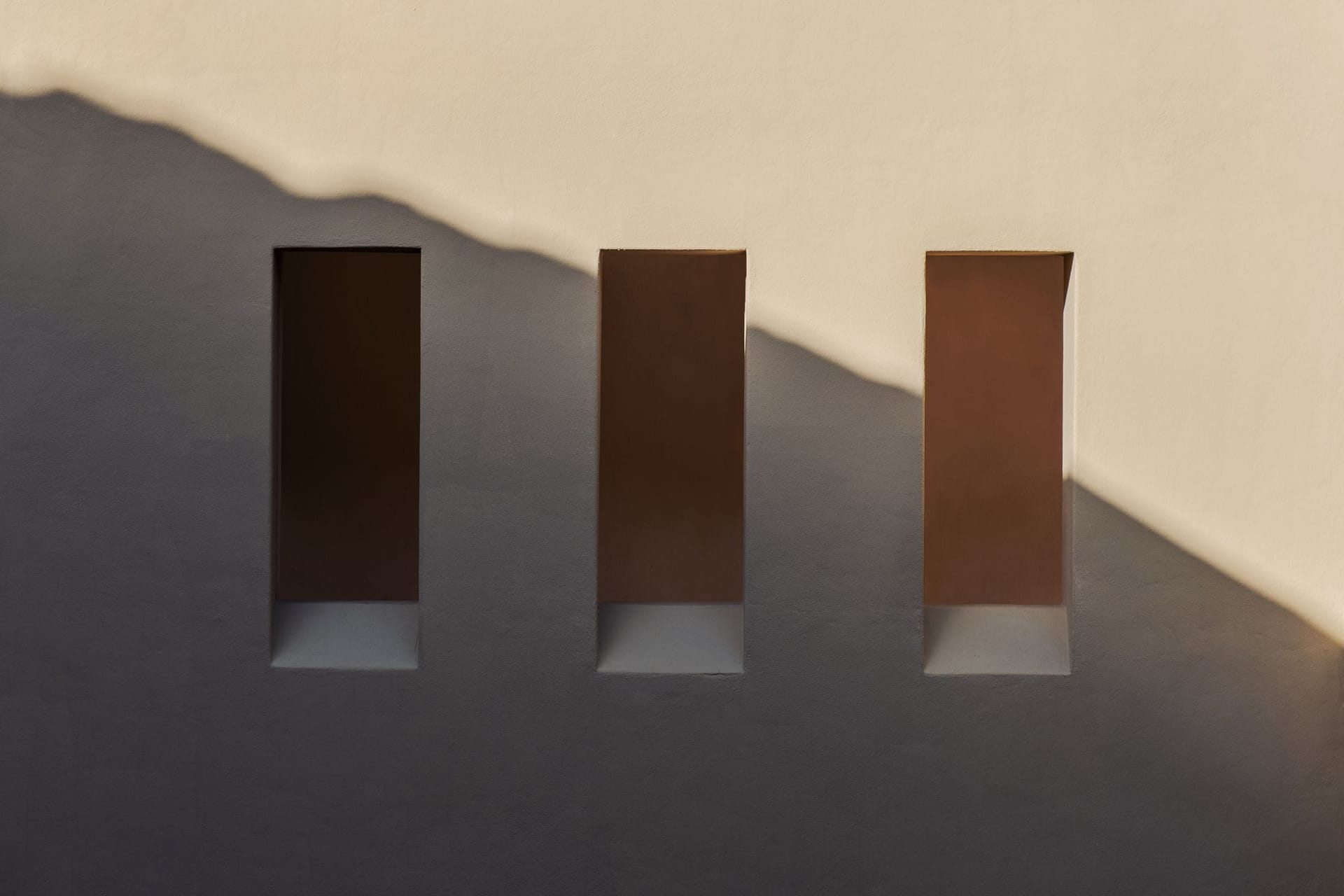 Ruhiges Architekturdetail: eine schlichte Fassade mit Schattenwurf am späten Nachmittag